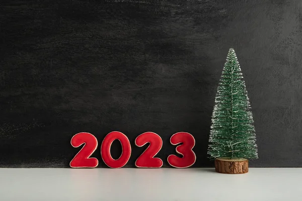人工的なクリスマスツリーと黒の背景に赤い数字2023 新年のコンセプト スペースのコピー — ストック写真