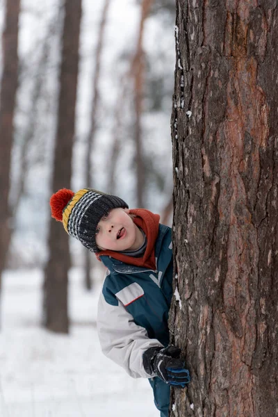 Αστείο Αγόρι Κρυφοκοιτάζει Πίσω Από Δέντρο Παιδί Πλεκτό Καπέλο Περπατά — Φωτογραφία Αρχείου
