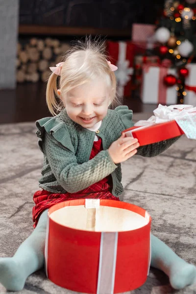 Little blonde girl opening Xmas presents. Desired present. Amazed little child opening Christmas gift