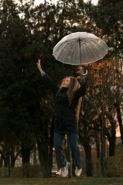 Счастливая Девушка Прыгает Прозрачным Зонтиком Руке Девушка Длинными Вьющимися Волосами — стоковое фото
