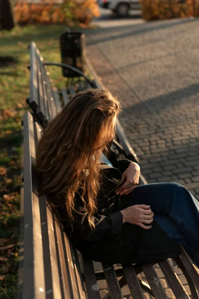 Uzun Kahverengi Saçlı Genç Bir Kadın Sonbahar Parkında Bankta Oturuyor — Stok fotoğraf