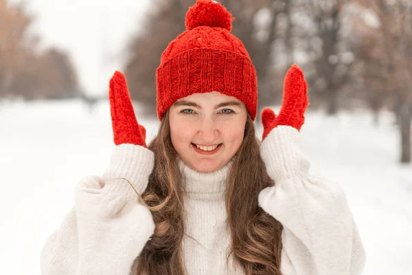 ニット帽とミトンで笑顔の若い女性の肖像画 冬の公園で女性が暖まる — ストック写真