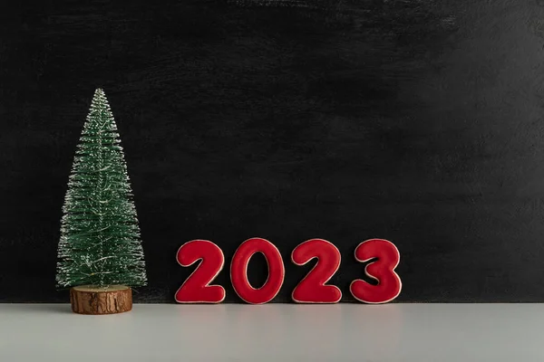人工的なクリスマスツリーと黒の背景に赤い数字2023 新年のコンセプト スペースのコピー — ストック写真