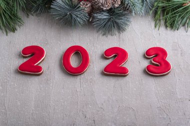 Kırmızı 2023 numara zencefilli çörek ve Noel çelengi. İyi yeni yıl ruhu. Arkaplanda açık gri duvar.
