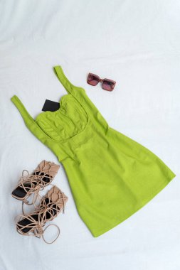 Green linen sundress on white background. Summer short dress with sandals and sunglasses.
