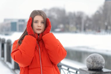 Kırmızı ceketli güzel bir kızın portresi ve dışarıda kışın örülmüş eldivenler. Moda gençliği kışlık giysileri.
