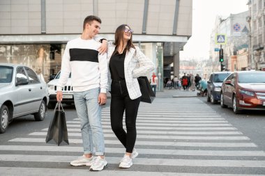 Cheerful young couple after successful shopping trip near the mall. Man And woman making purchases together