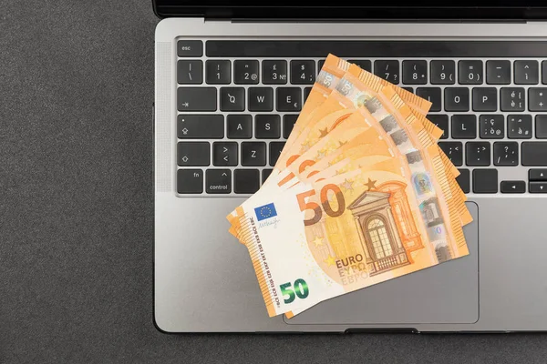 Euro cash on your laptop top view. Banknotes on keyboard. Earnings on the Internet. Remote work. Buy online