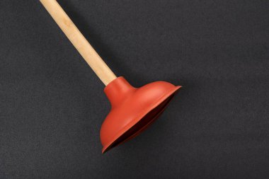 Toilet plunger on black background. Red rubber cup plunger. Plumbers drain cleaner tool. Equipment for clearing blockages