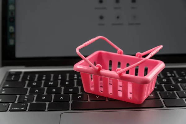 Pink shopping cart on laptop keyboard. Online shopping. Shopping on the Internet. Online store