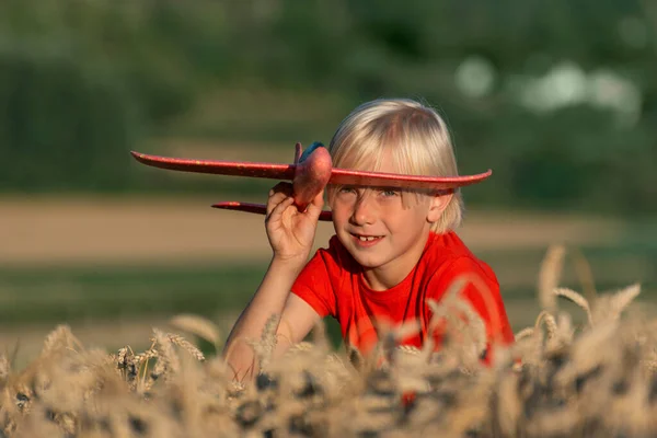 Světlovlasý Chlapec Červeném Tričku Drží Červený Model Letadla Sedí Zralém — Stock fotografie