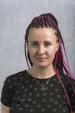 Gri arka planda pembe yapay rastalı beyaz kadın portresi. Dikey çerçeve.