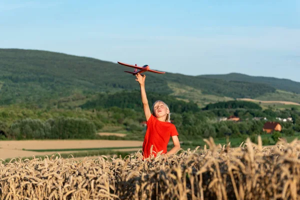 Šťastný Blonďatý Chlapec Hračkou Letadlo Pšeničném Poli Horském Pozadí Lety — Stock fotografie