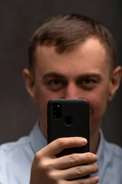 男人在电话或自拍中拍照 黑色智能手机在人类的背景下被聚焦 垂直框架 — 图库照片