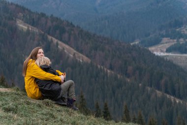 Anne ve oğlu dinleniyor ve dağlarda bir kucakta oturuyor. Genç kadın ve çocuk yamaçta oturuyor..