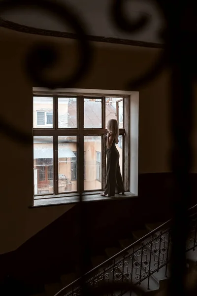 Σιλουέτα Της Νεαρής Γυναίκας Μαύρο Παντελόνι Στέκεται Στο Περβάζι Του — Φωτογραφία Αρχείου