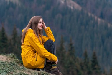 Orman arka planında yamaçta uzun saçlı güzel beyaz kadın portresi. Turist kızın yaşam tarzı.