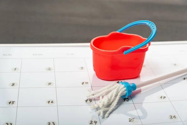 Small bucket and mop on calendar. Planned cleanup. Concept of spring general cleaning