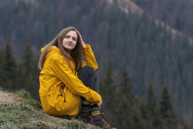 Orman arka planında yamaçta uzun saçlı güzel beyaz bir kadının yaşam tarzı portresi.