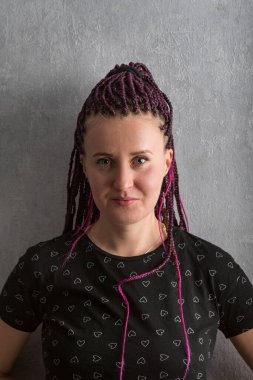 Pembe örgülü modern genç bir kadın ya da gri arka planda dehşet saçan bir kadın ileride görünüyor. Dikey çerçeve