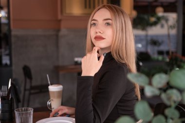 Yazlık kafede dalgın genç bir kızın portresi. Çekici genç sarışın kadın kafede masada oturur ve dışarıya bakar..