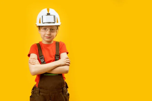 穿着工作服的男孩的画像 黄色背景的防护头盔和眼镜 选择专业概念 复制空间 — 图库照片