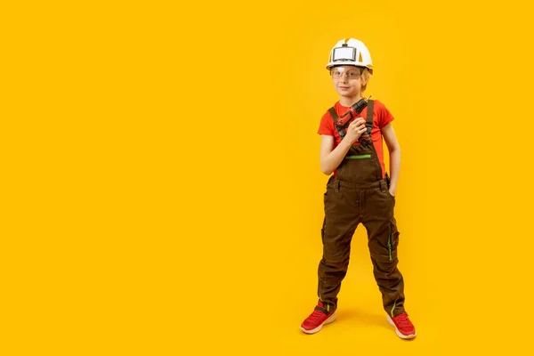 노란색 배경에서 일하는 아이들은 보호용 헬멧을 드릴을쥐고 있습니다 흉내내봐 — 스톡 사진