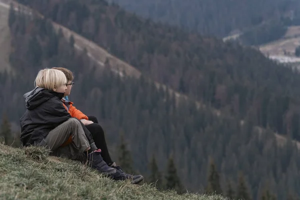 stock image Two boys are sitting on hillside. Portrait of children in autumn in the mountains. Weekend in nature outside