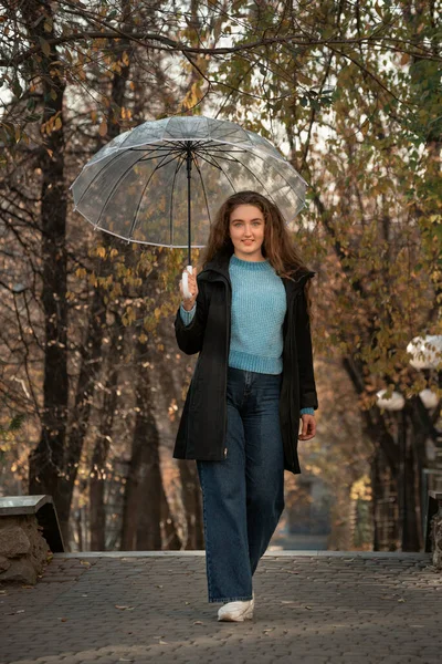 秋の公園で透明傘で立って緑豊かな髪の若い女性 公園の女性の写真 — ストック写真