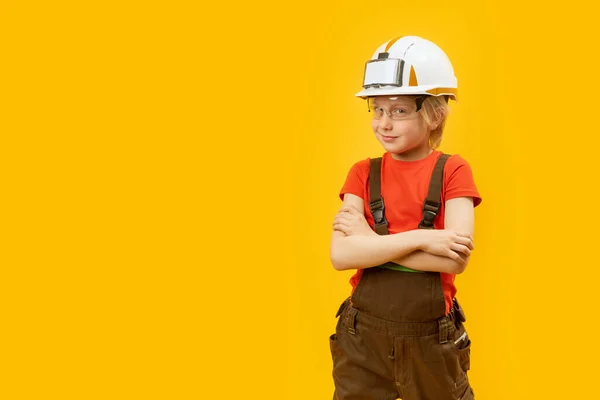 面带微笑的男孩像工人一样戴着防护头盔 戴着眼镜 穿着连衣裙 黄色背景 复制空间 — 图库照片