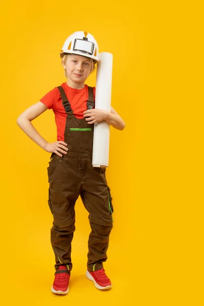 穿着防护头盔 工作服 手上拿着纸片或绘图的男孩的画像 作为建设者或建筑师的孩子 垂直框架 — 图库照片