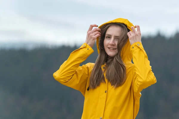 stock image Portrait of young woman in yellow raincoat outside. Girl on hike in autumn look at camera