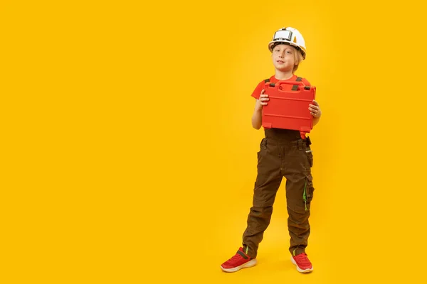 模仿工人的男孩的全长肖像 孩子们戴着头盔 把工具箱隔离在黄色的背景下 复制空间 — 图库照片