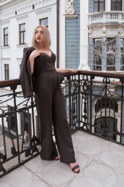 Genç kendine güvenen girişimci kadın balkonda duruyor. Açık havada siyah takım elbiseli başarılı bir kadın..