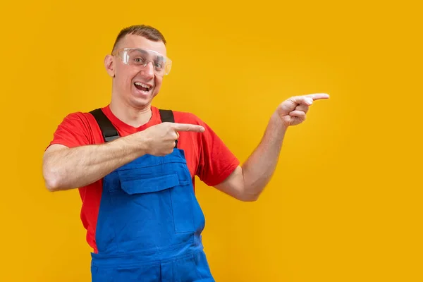 Trabalhador Construção Masculino Alegre Macacão Azul Óculos Aponta Seus Dedos — Fotografia de Stock