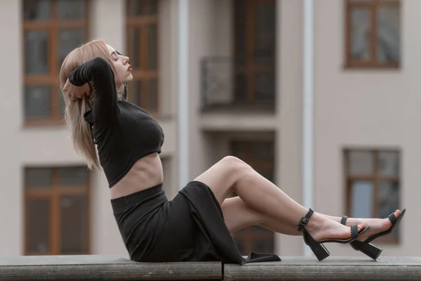 黒の服とヒールでブロンドの髪を持つスタイリッシュな魅力的な若い女性 市内の美しい女の子 — ストック写真