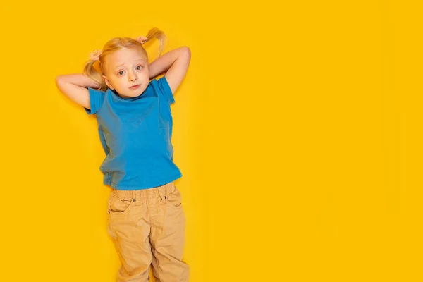 노란색 배경에 아이의 티셔츠를 소녀가 있습니다 — 스톡 사진