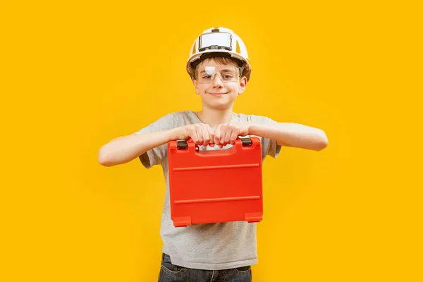 白人青少年男孩戴着防护头盔 眼镜则带着黄色背景的仪器盒 小孩喜欢建筑工人 职业选择 — 图库照片