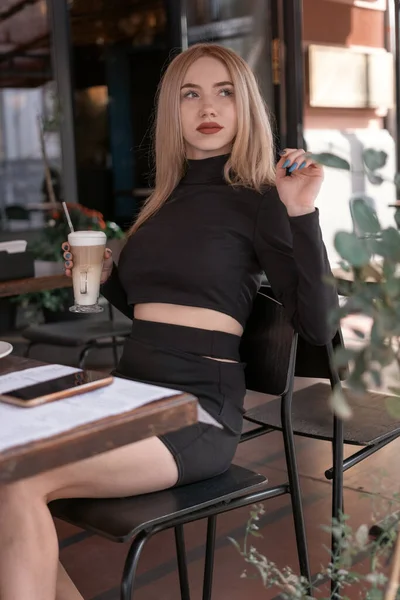Стильная Молодая Женщина Обтягивающей Черной Одежде Сидит Столом Кафе Держит — стоковое фото