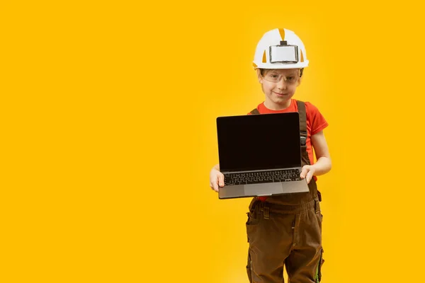 穿着工作服和防护头盔的男生拿着装有空屏幕的笔记本电脑 作为建筑师的孩子未来职业的选择 复制空间 — 图库照片