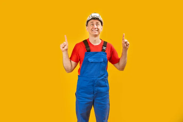 穿着制服的建筑工人或工程师感到害怕或困惑 头盔将他的食指指向黄色孤立的背景 复制空间 — 图库照片