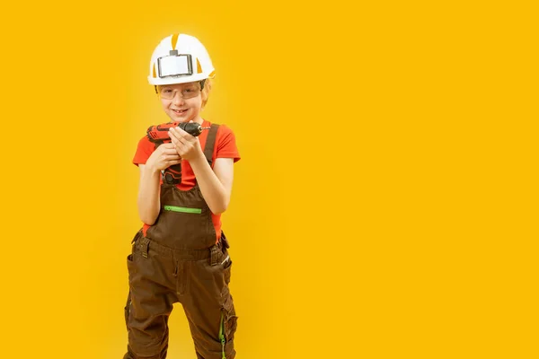 男孩作为建设者 戴白色头盔的儿童 戴着防护眼镜 穿着工作服 举行演练 被黄色背景隔离 复制空间 — 图库照片