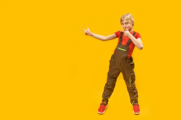 Хлопчик Підліток Комбінезоні Позує Студії Жовтому Тлі Вказує Пальці Бік — стокове фото