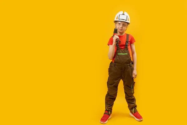 아이들은 보호용 헬멧을 드릴을쥐고 있습니다 노란색 배경에서 일하는 흉내내봐 — 스톡 사진
