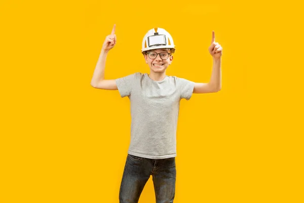 笑容满面的小伙子穿着T恤牛仔裤 戴着防护头盔 用食指尖着他的食指 复制空间 案文的篇幅 — 图库照片