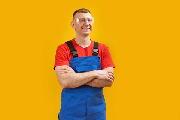 身穿蓝色工作服的中年工程师面带微笑 双臂交叉 隔离在黄色背景之下 复制空间 — 图库照片