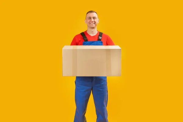 身穿蓝色制服的信使手里拿着一个大包裹 复制空间 带黄色背景纸盒的送货员 — 图库照片