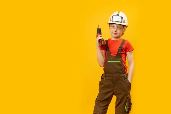 穿着工作服的男孩的画像 手里拿着钻头的头盔 建筑工人的作用 复制空间 职业选择 — 图库照片