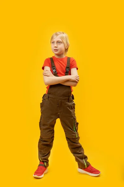 明るい黄色の背景にブロンドの髪を持つ白人少年の完全な長さのスタジオの肖像画 — ストック写真