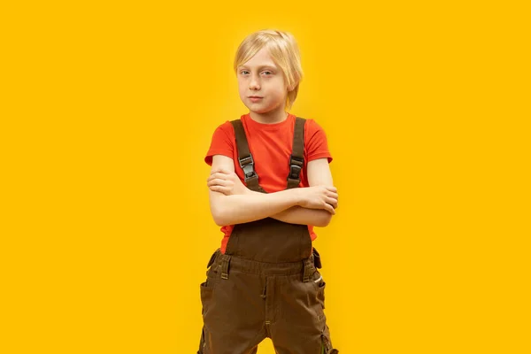 黄色を背景にスタジオでポーズをとったジャンプスーツと赤いTシャツを着た金髪の白髪の少年の肖像 スペースのコピー — ストック写真